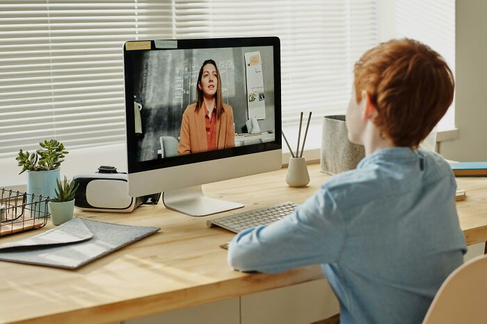 Child on a video call with a babysitter, engaged in an online learning session from home.