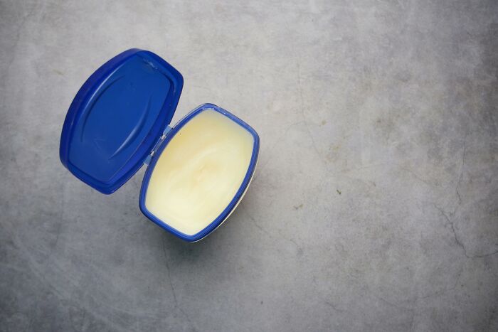 Open jar of petroleum jelly on a gray surface, illustrating unexpected babysitting moments.