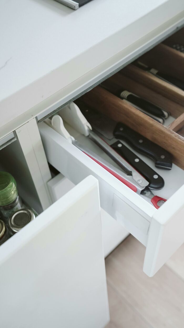 Open kitchen drawer with knives and scissors, representing babysitters' concerns for kids' safety.