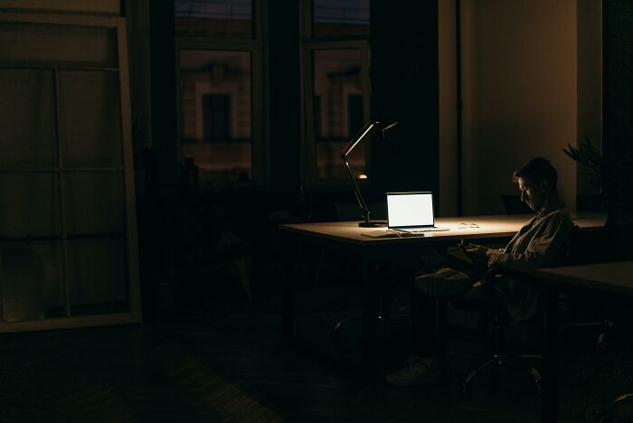 Person working late in dim room with laptop, illustrating a bad-good-habit of nighttime productivity.