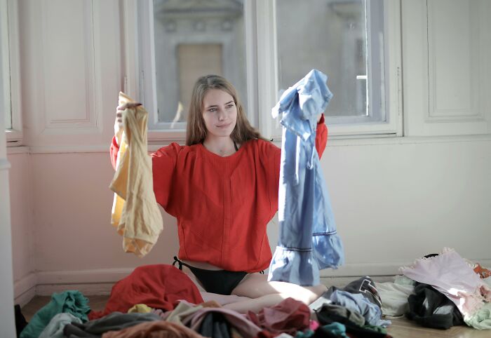 Woman choosing between clothes, sorting through laundry, illustrating decision-making in forming a bad-good-habit.