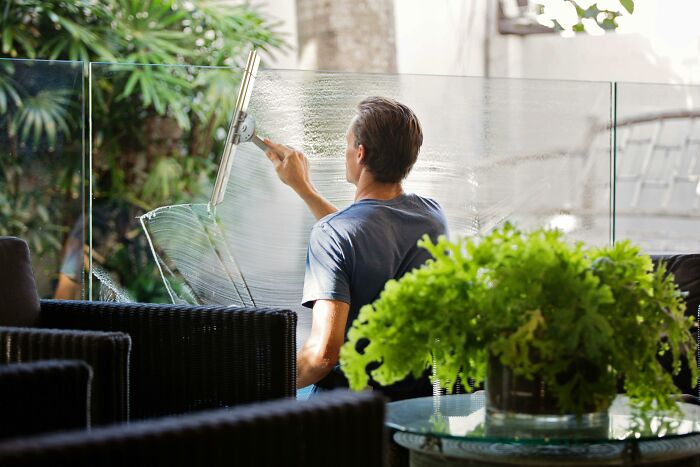 Person cleaning a glass window with a squeegee, showcasing good habits in maintaining cleanliness.