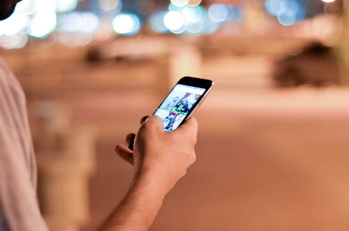 Person holding a smartphone, illustrating bad-good-habit of frequent device use in a blurred urban setting.