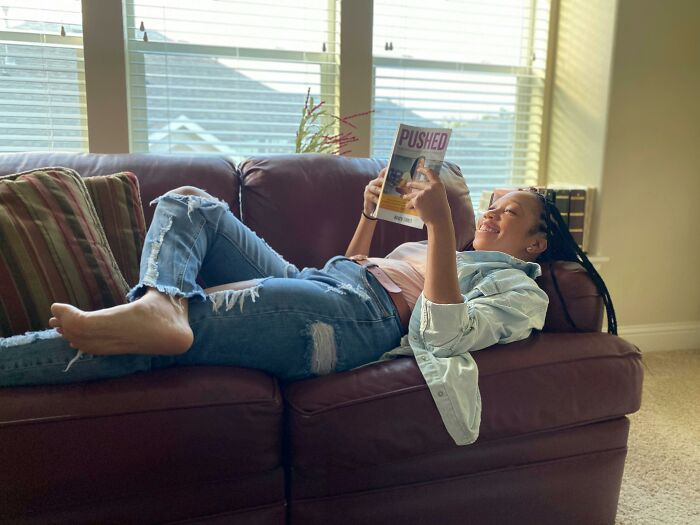 Woman reading a magazine on a sofa, highlighting a relaxed good habit.