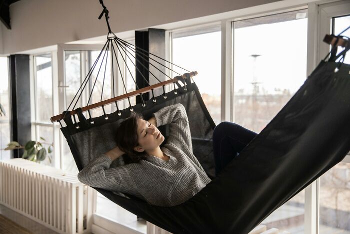 Person relaxing in a hammock indoors, illustrating a good habit.