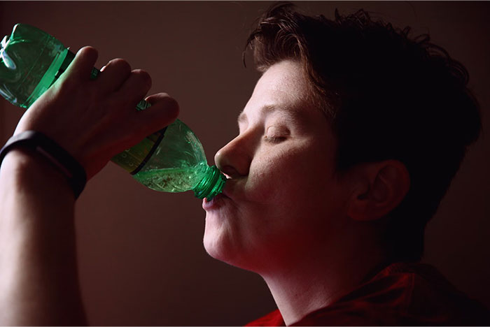 Person drinking from a green bottle, demonstrating a casual moment possibly related to school presentations.