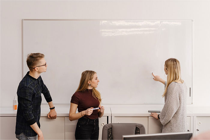 Students in class discussing a blank whiteboard during a school presentation.