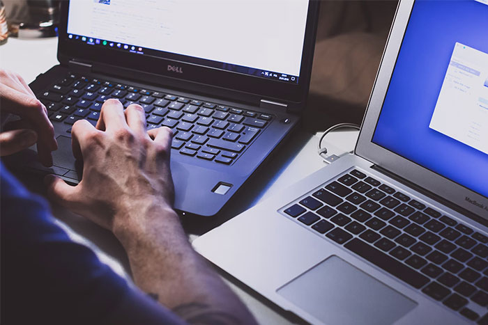 Person using a Dell laptop next to another laptop, potentially related to school presentations.