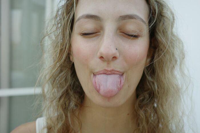 Person with eyes closed and tongue out, highlighting hygiene habits.