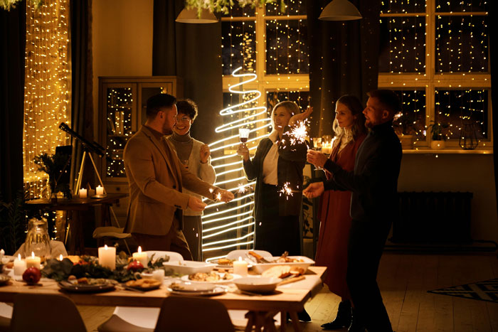 People celebrating Christmas with sparklers, festive lights, and a decorated dining table, creating a warm holiday atmosphere.