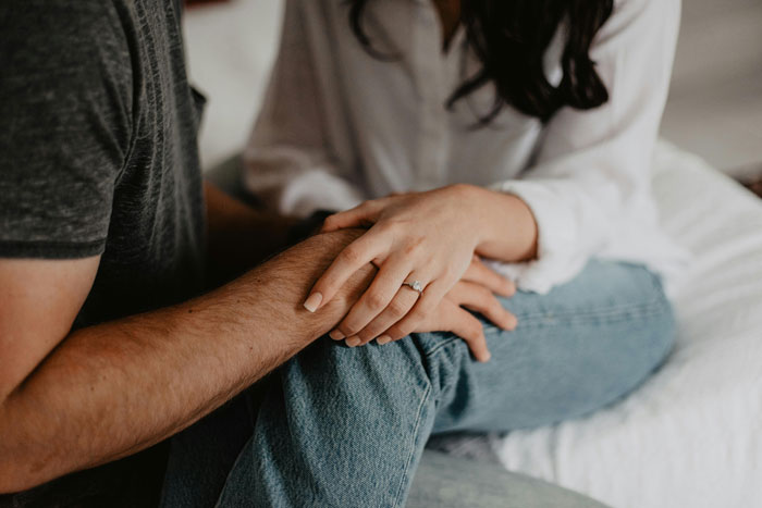 Couple holding hands, showcasing an engagement ring, symbolizing brother wedding engagement moment.