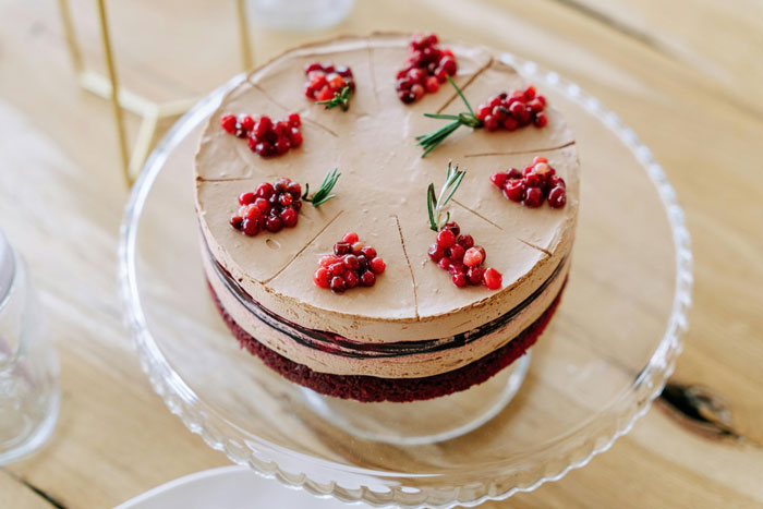 Chocolate cake with berries and rosemary on a glass stand, ready for a friend's birthday party celebration.