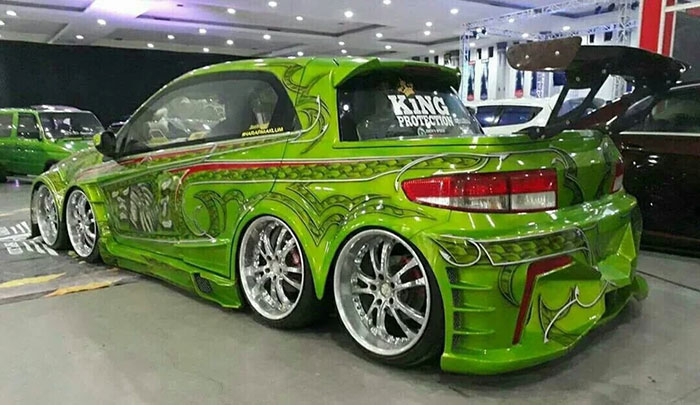 Customized green car with an intricate paint job and oversized wheels on display, showcasing car-fails in extreme modifications.