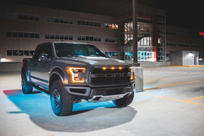 Truck parked in a hotel parking lot at night, bright headlights illuminating the area.