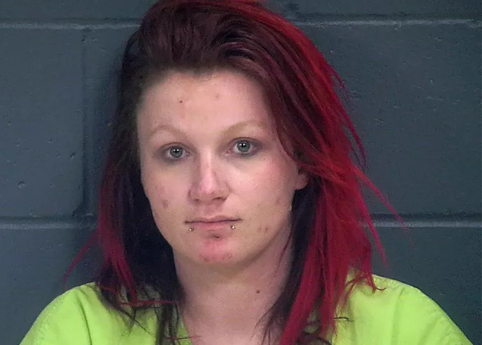 Chelsea O'Donnell in a mugshot, wearing a green top, in front of a cinder block wall.