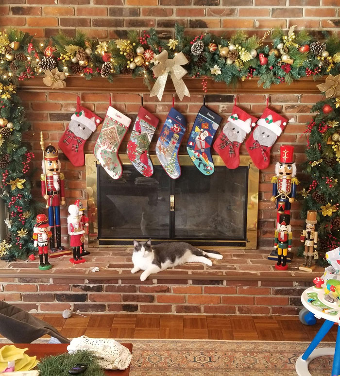 Christmas decorating ideas with stockings and nutcrackers on a festive fireplace, with a cat lying on the hearth.