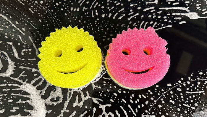 Two colorful sponges with smiley faces on a soapy surface, resembling christmas-gift-early ideas.