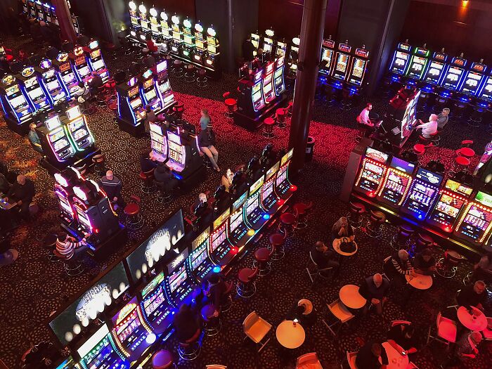 Aerial view of a busy casino floor filled with colorful slot machines and patrons.