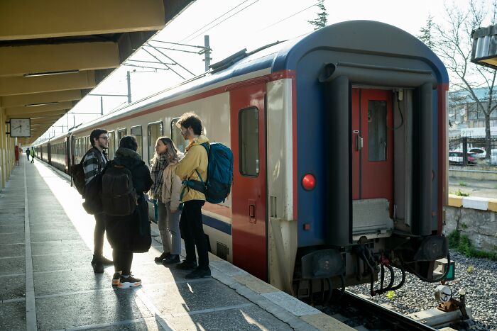 Travelers in conversation by a train at a station, backpacks on, illustrating various travel situations.