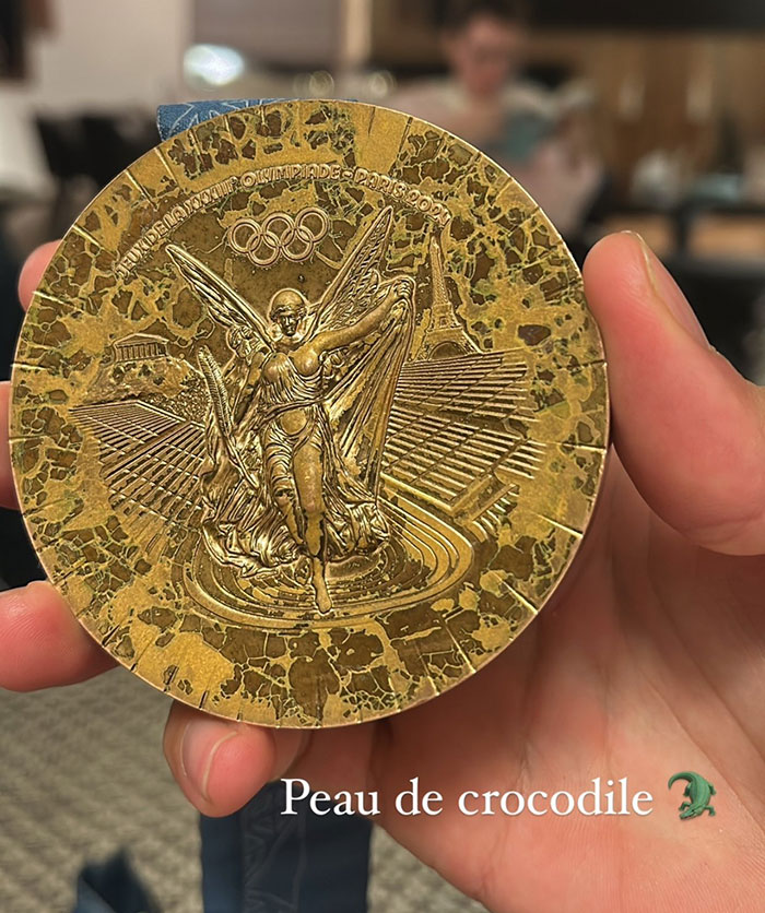 Rusted bronze medal from Paris 2024 Olympics, showing detailed artwork and design.