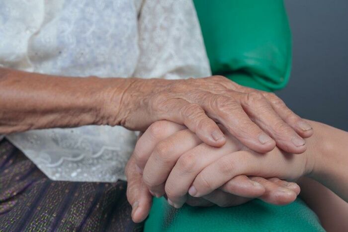 Elderly and young hands clasped together, symbolizing challenges of aging.