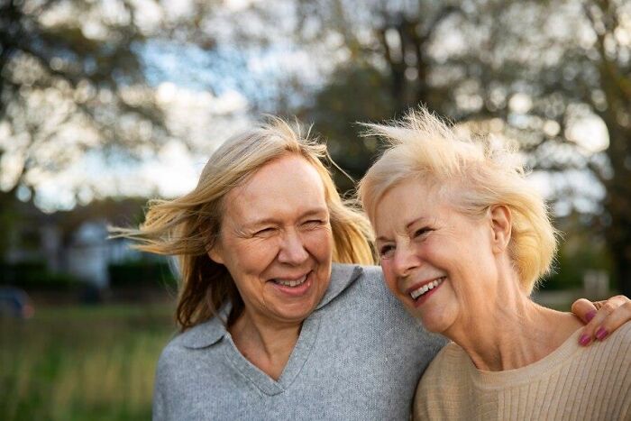 Two older women smiling outdoors, representing unexpected challenges of aging.