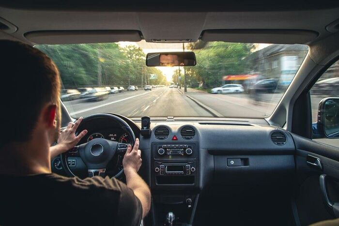 Driver navigating through city roads at sunset, reflecting on challenges of aging.