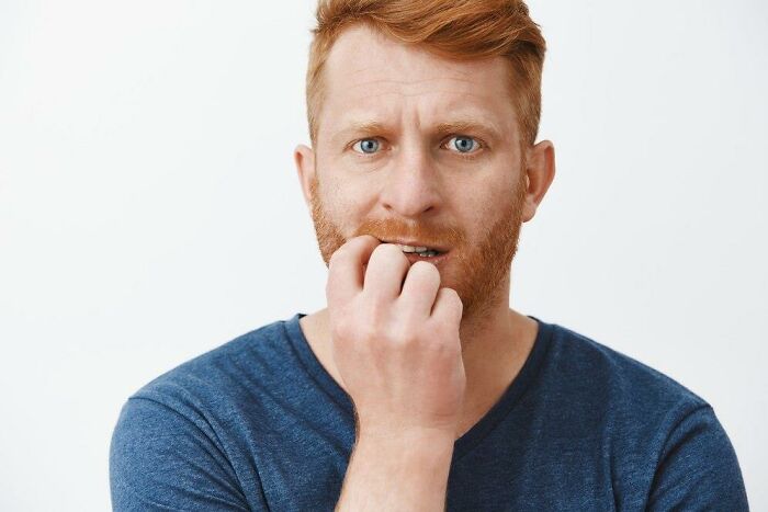 Man with red hair and blue eyes looking concerned, reflecting on partner's weird habits after moving in together.