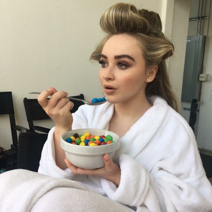 Person in a robe eating colorful candies from a bowl, highlighting partner’s weird habits.