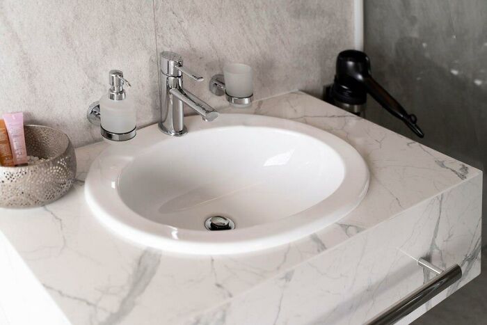 Marble bathroom sink with cluttered items, highlighting partner's weird habits after moving in together.