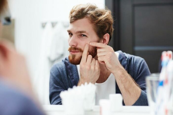 Man discovering partner's weird habit of face-picking in the bathroom mirror, highlighting unexpected behaviors in relationships.