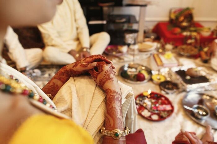 Bride with hennaed hands at a ceremony, surrounded by traditional items, highlighting worst things happen at a wedding.