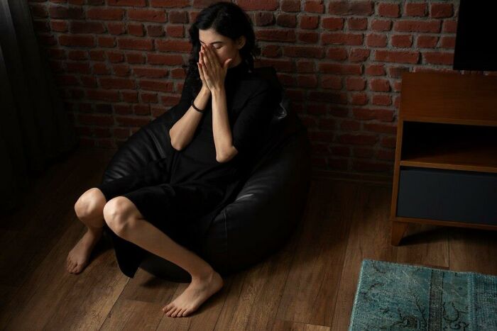 A woman seated on a bean bag, looking upset, reflecting the theme of a terrible Christmas experience.