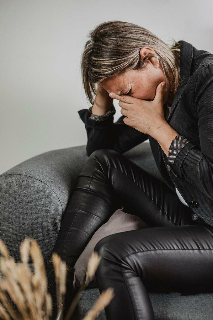 Person in distress on a sofa, covering their face, having a terrible Christmas.