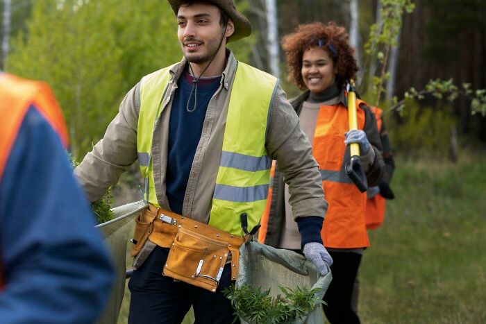 People in reflective vests gardening in a park, holding tools and bags, illustrating crazy stories of HR not being your friend.