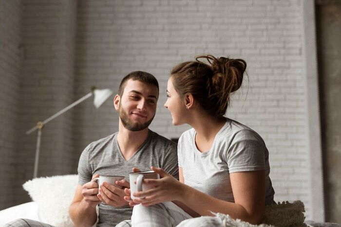 Couple in cozy setting, woman inquiring about man's thoughts over coffee, showcasing curious interaction.