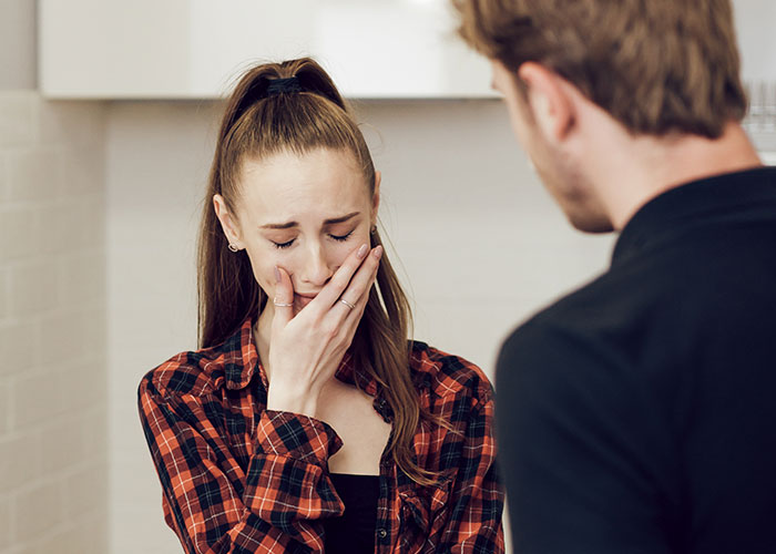 A woman in a plaid shirt appears upset, facing a man; illustrating shocking comments affecting relationships.