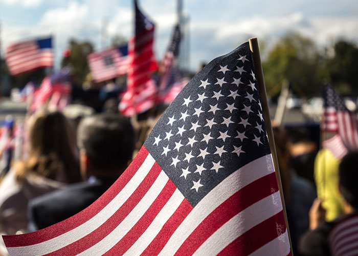 American flags waving at an outdoor gathering, symbolizing national pride and unity.