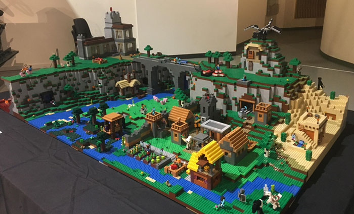 Intricate Cool-LEGO-Builds diorama featuring a landscape with houses, trees, and a dragon atop a mountain.