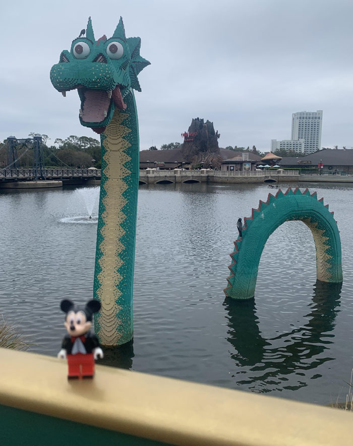 LEGO sea serpent sculpture in a lake with a Mickey Mouse figure in the foreground, showcasing cool LEGO builds.