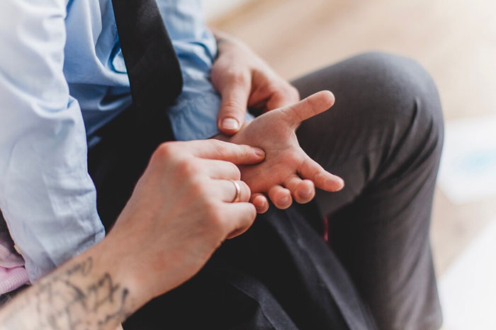 Person demonstrating a crazy body life hack using acupressure on a man's hand.