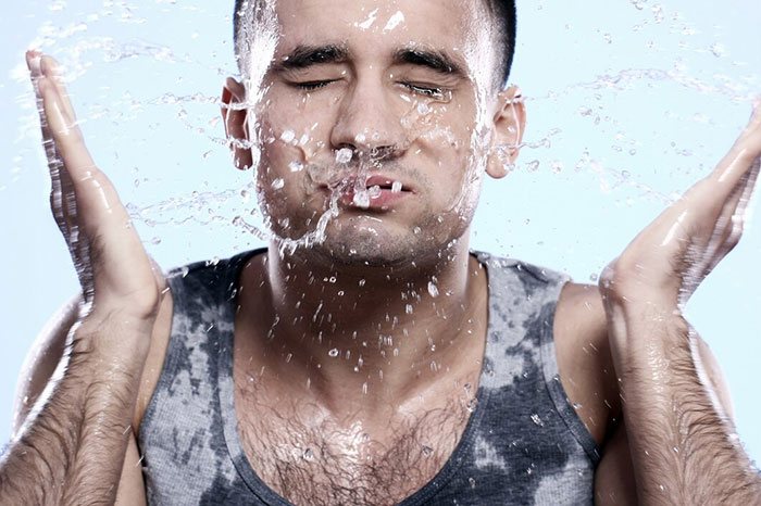 Person splashing water on face, enjoying refreshing life hack.