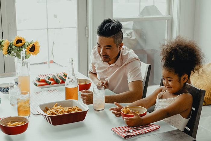 Father and daughter enjoying a meal together, with watermelon and sunflowers in the background, relating to crazy body life hacks.