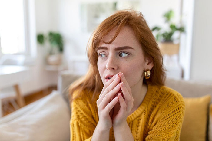 Woman in a cozy living room, wearing a yellow sweater, contemplating crazy body life hacks.