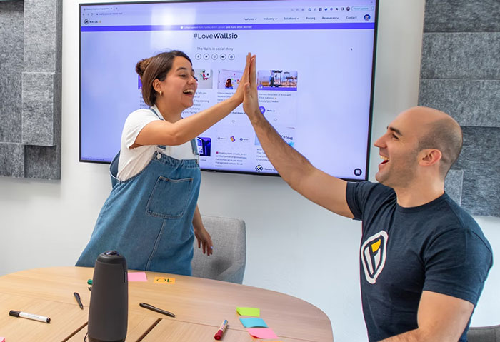 Two people high-fiving in a casual office setting, exemplifying teamwork and creative body life hacks.