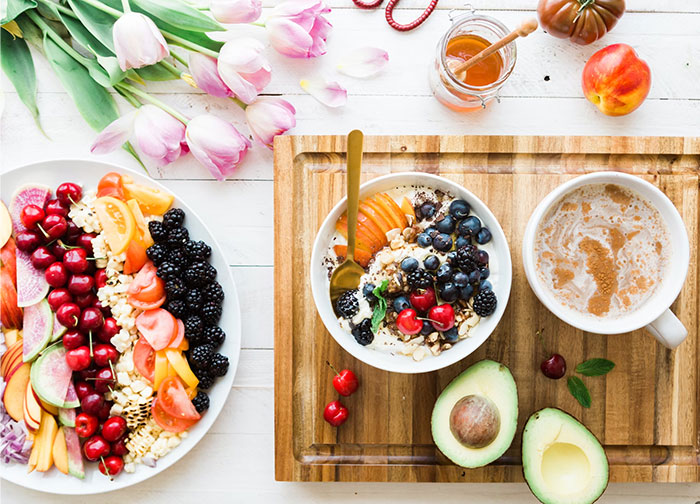 Fresh fruits and nuts as a crazy body life hack for healthy eating on a wooden board with coffee and tulips.