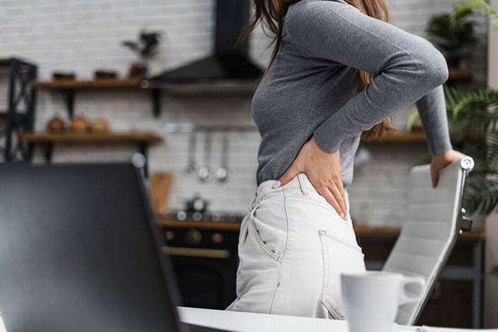 Person using body hack for back pain relief in a home office setting.