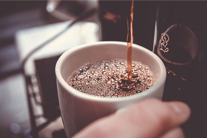 Pouring coffee into a mug, showcasing a simple body life hack.