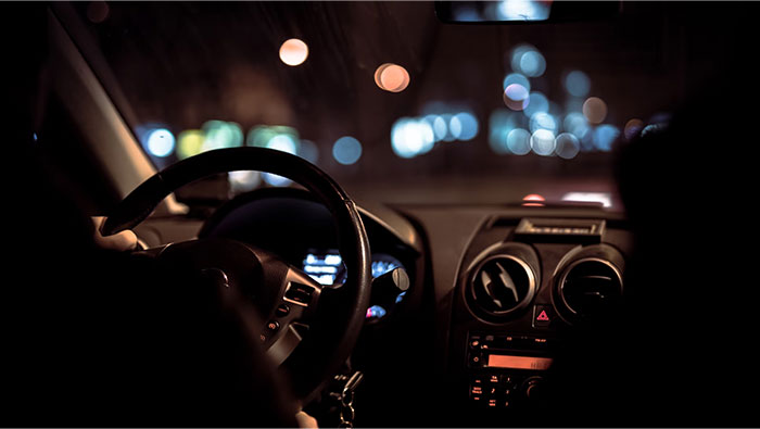 Driving at night with blurred city lights, illustrating crazy body life hacks for alertness.