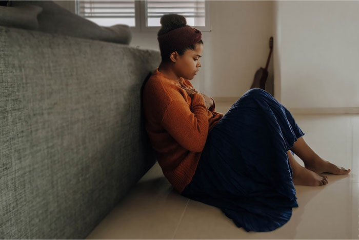 Woman in cozy outfit sitting against a couch, illustrating a peaceful moment related to life hacks.